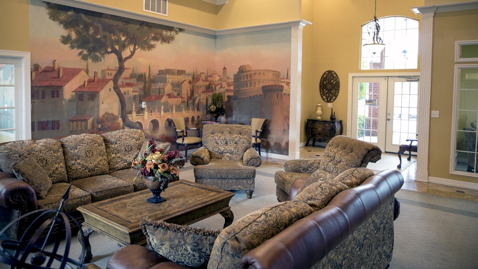 Stone Creek Apartments Welcome Center interior couches and chairs with a mural of Rome on the wall behind